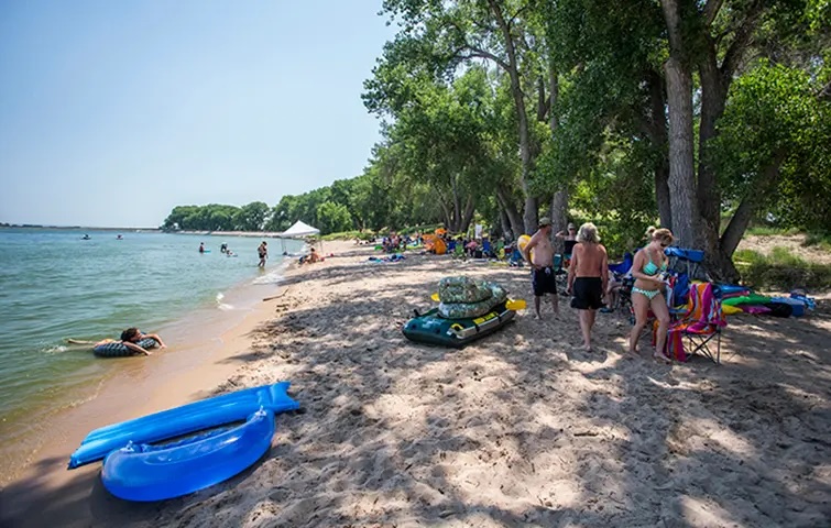 Swimmers, kayaks and beach chairs along the sandy shoreline at Jackson Lake State Park